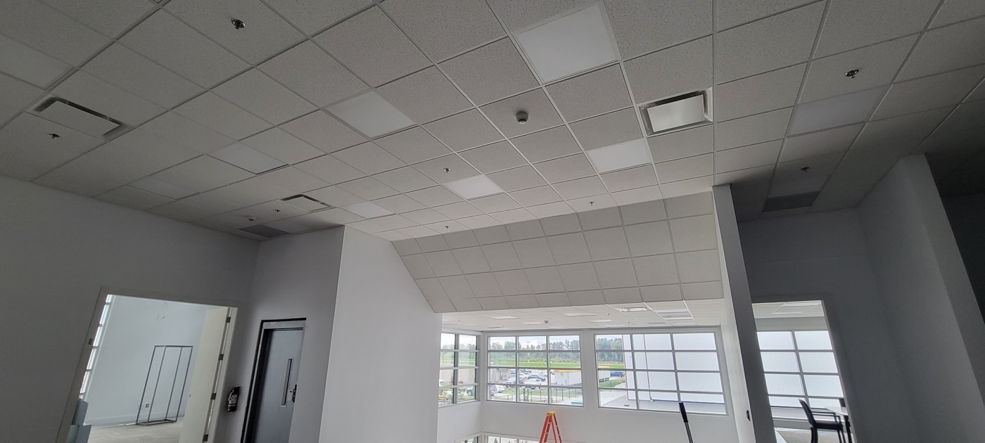 Finished suspended acoustic tile ceiling in a bright commercial room. Finished suspended acoustic tile ceiling in a bright commercial room.